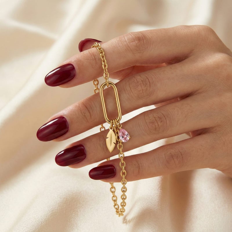 This attractive gold bracelet, crafted from rust-resistant stainless steel, features a modern link ring from which a delicate feather and a sparkling pink stone dangle. It has an adjustable clasp for a perfect fit. - Image 3